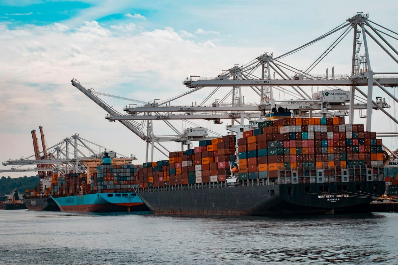 Movimentazione container in un terminal portuale al crepuscolo per flussi doganali
